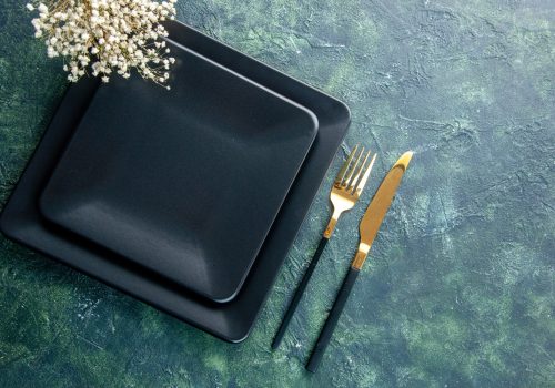 top-view-black-square-plate-with-golden-fork-knife-dark-background-color-food-cutlery-dinner-kitchen-restaurant-free-space